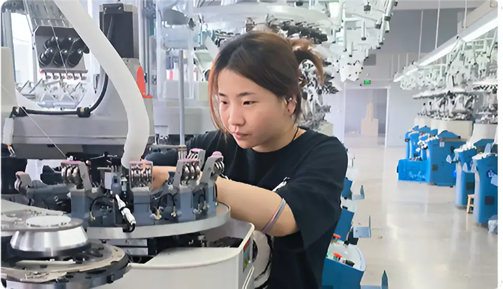 Young woman operating a sock knitting machine in a modern textile factory, showcasing advanced knitting technology for high-quality sock production.