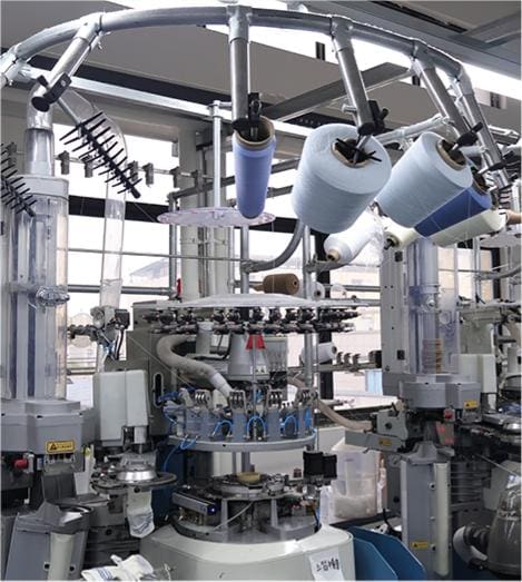 Advanced textile knitting machine with multiple spools of yarn.