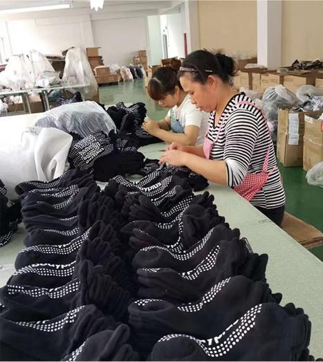Workers sorting and inspecting socks on a production line in a factory setting.
